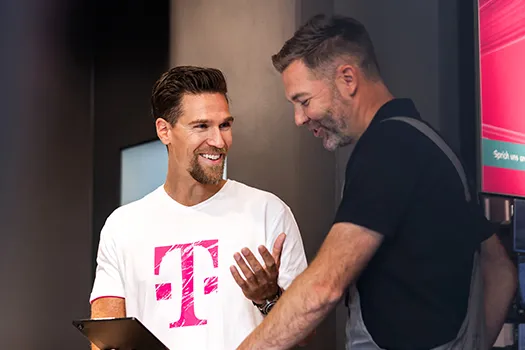 Telekom Mitarbeiter berät Kunden im Shop, beide lächeln und sprechen miteinander
